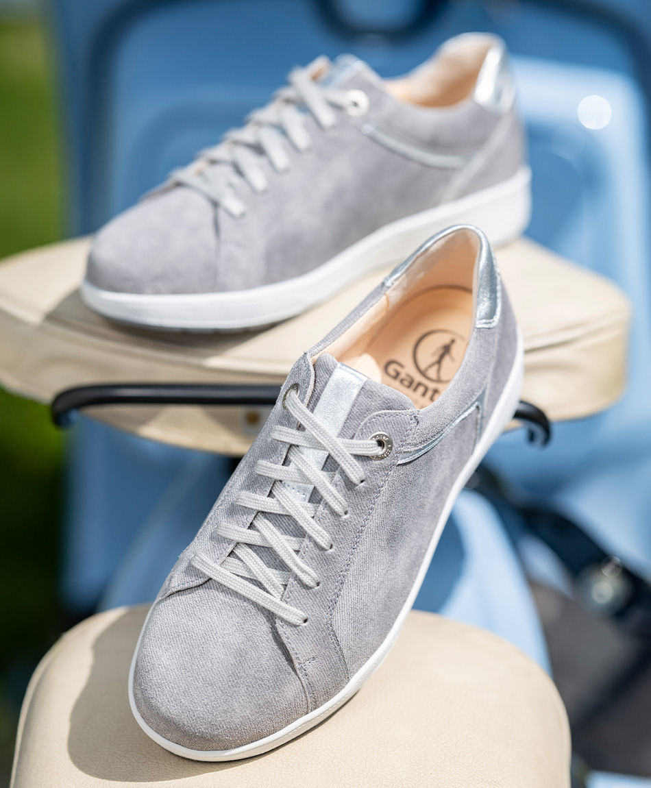Auf einem hellen Stuhl befinden sich graue Sneaker